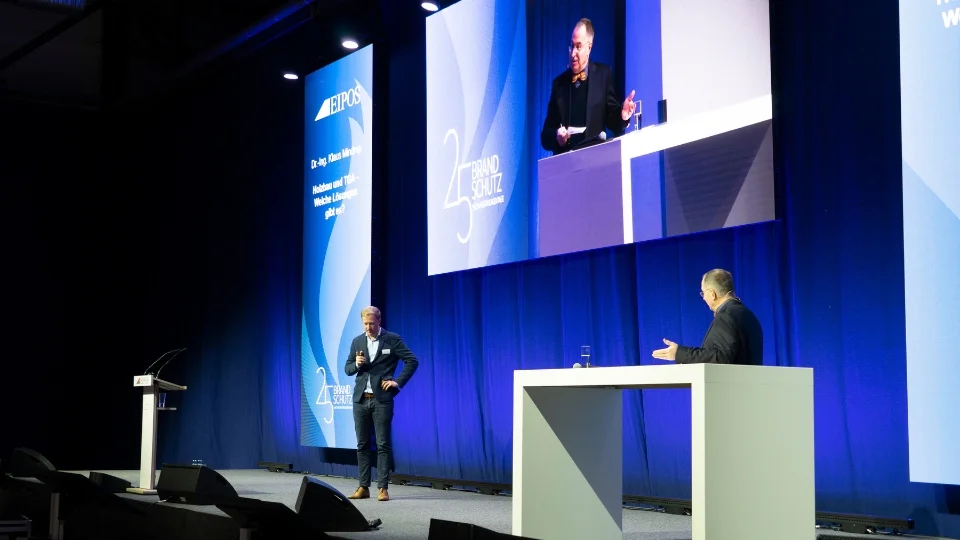 Blick auf die Bühne mit zwei Rednern in einem Gespräch miteinander