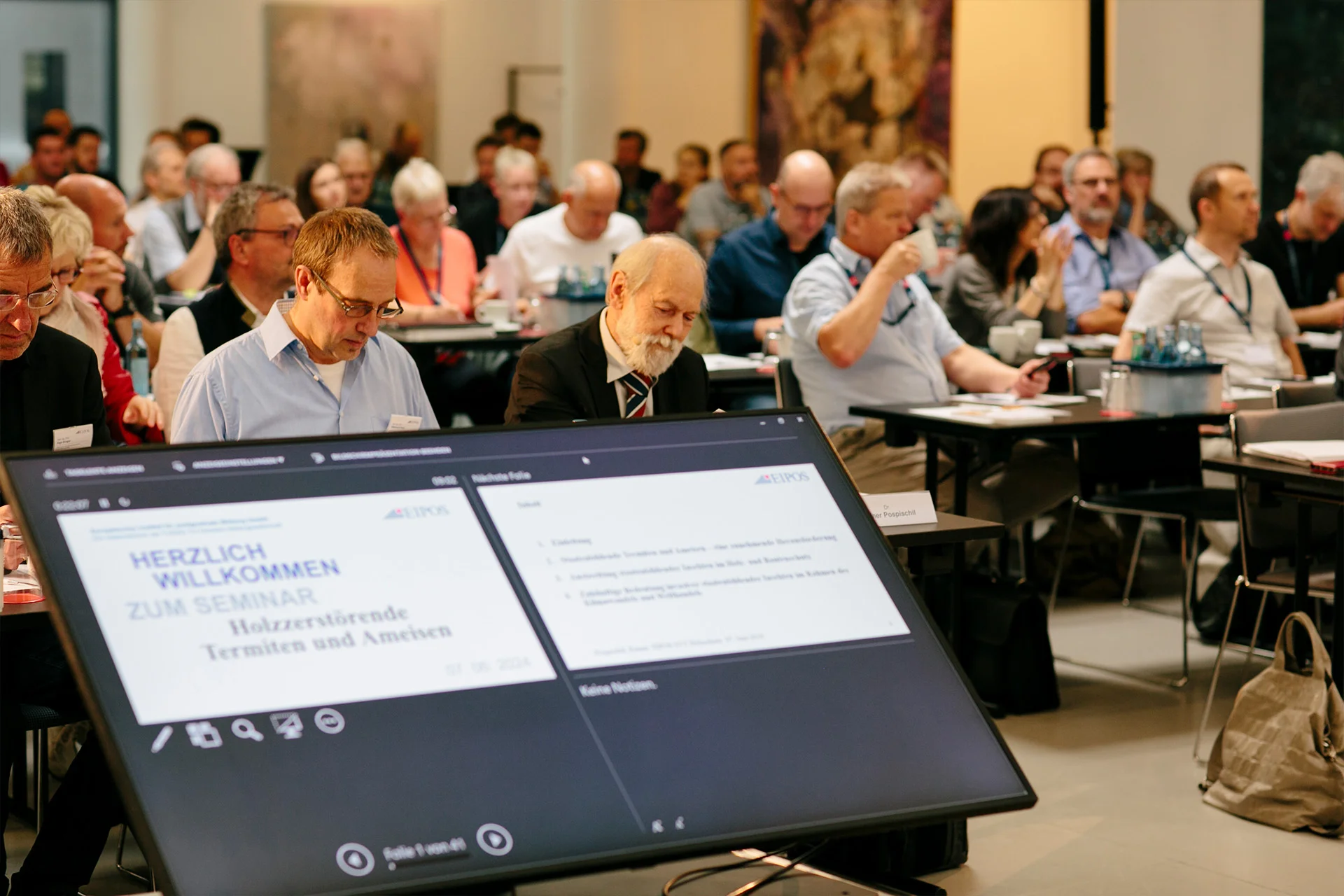 Blick von der Bühne ins Publikum mit dem Bildschirm für die Referentenansicht der Präsentation im Vordergrund