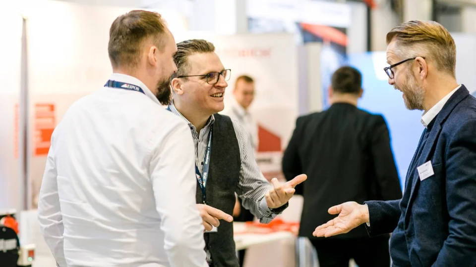Aufnahem einer begeisterten Diskussion zwischen 3 Herren im Ausstellungsbereich