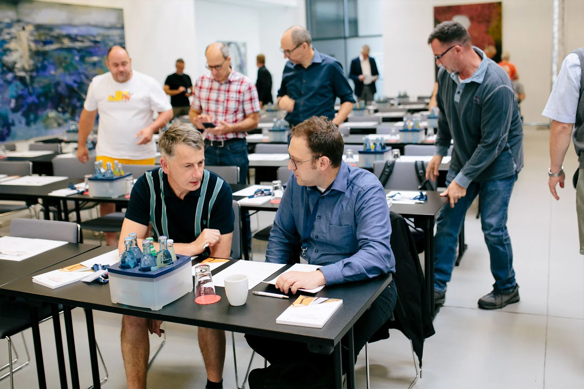 Aufnahme des sich füllenden Konferenzraumes mit einigen Teilnehmern in ein Gespräch miteinander vertieft