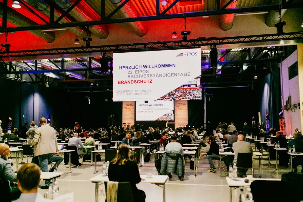 EIPOS Sachverständigentage Brandschutz 2021 - Blick von der Rückseite des Saals über die Teilnehmer zur Bühne 