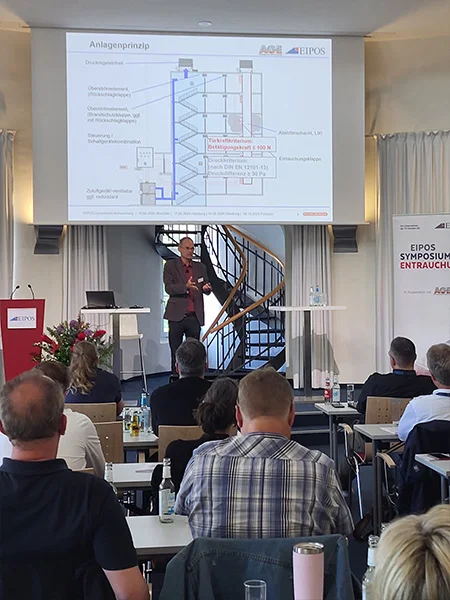 Aufnahme eines Redners mit seinem Foliensatz auf der Leinwand über ihm